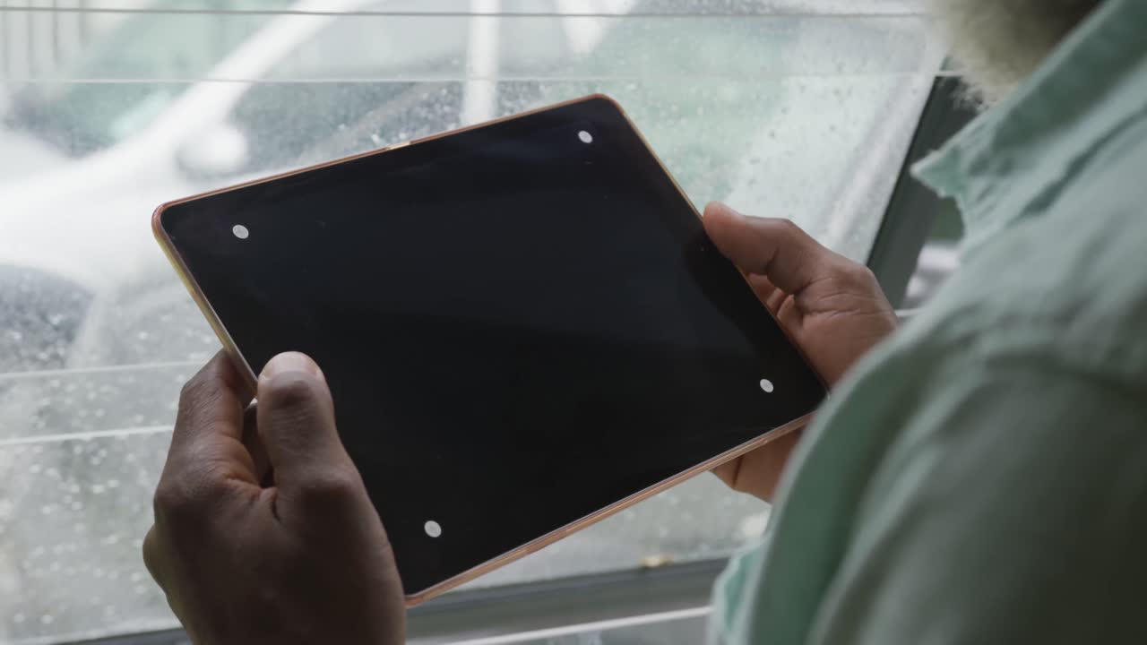 Video of african american senior man using tablet with black screen