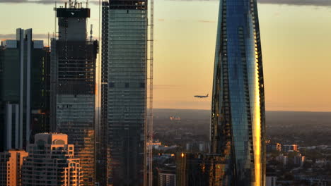 airplane approaching sydney airport behind the ultra modern skyscrapers in the city at sunset