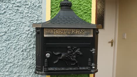 black forge horse wall mounted letter box outside a colourful house