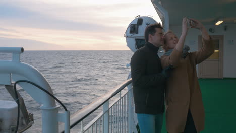 young couple making phone selfie on shipboard