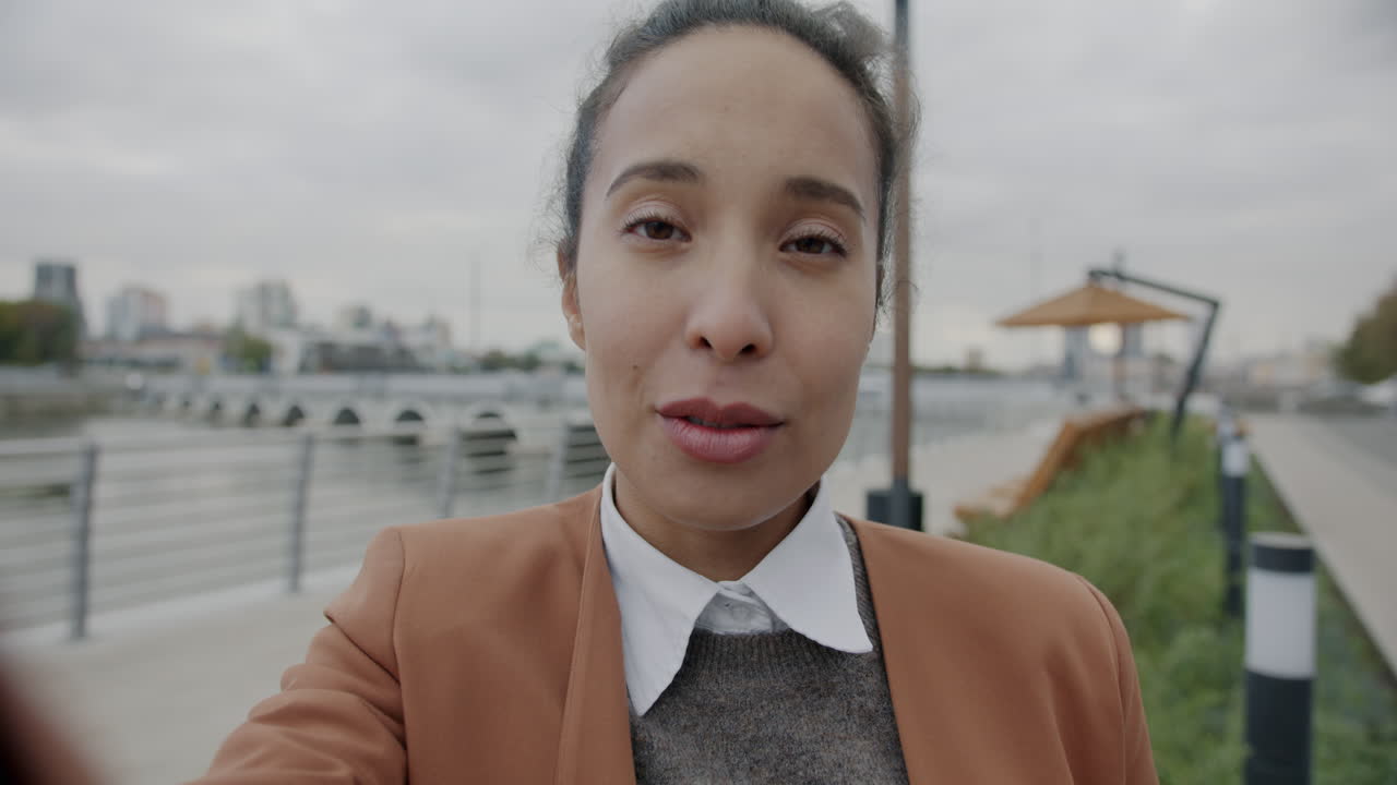 Woman taking a selfie outdoors by a river and bridge.