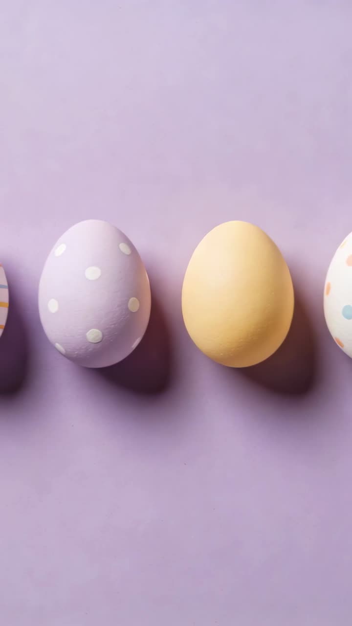 Panning camera revealing decorated pastel eggs on purple tabletop, showing soft shadows beneath