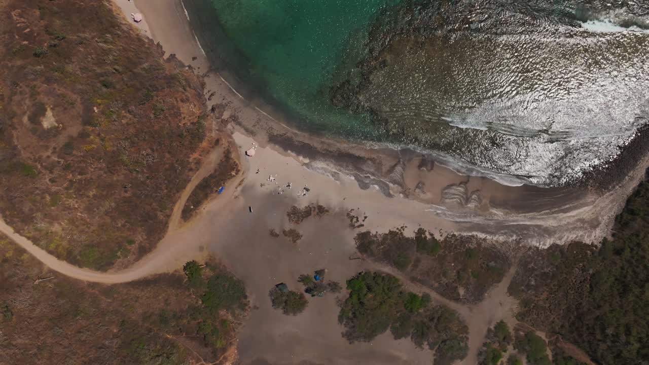 Top-down aerial over La Morita beach showing crystal-clear waters with visible underwater coral reefs at low tide. Tenacatita, Mexico