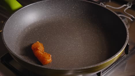 chef is frying pieces of chicken on a hot pan, using a kitchen tong