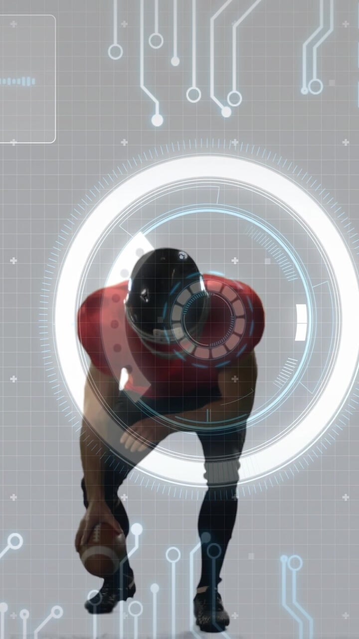 Reagendo al bagliore dell'HUD, un giocatore con casco e protezioni rosse che si muovono, prepara lo snap con il pallone da football in studio.