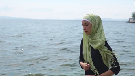 young woman in hijab walking on the beach