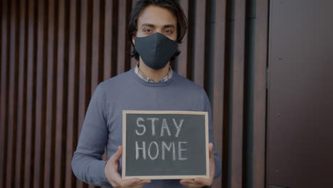 man holding a sign that says 'stay home' during a pandemic.