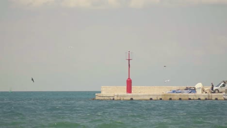 Stunning-HD-footage-of-a-red-lighthouse-at-the-end-of-Koper-harbor,-surrounded-by-the-waves-of-the-Adriatic-Sea