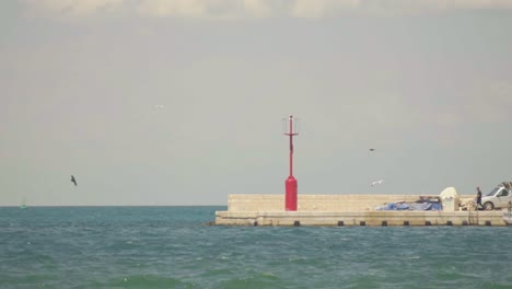 impresionantes imágenes en hd de un faro rojo al final del puerto de koper, rodeado por las olas del mar adriático