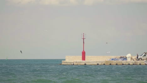 stunning hd footage of a red lighthouse at the end of koper harbor, surrounded by the waves of the adriatic sea