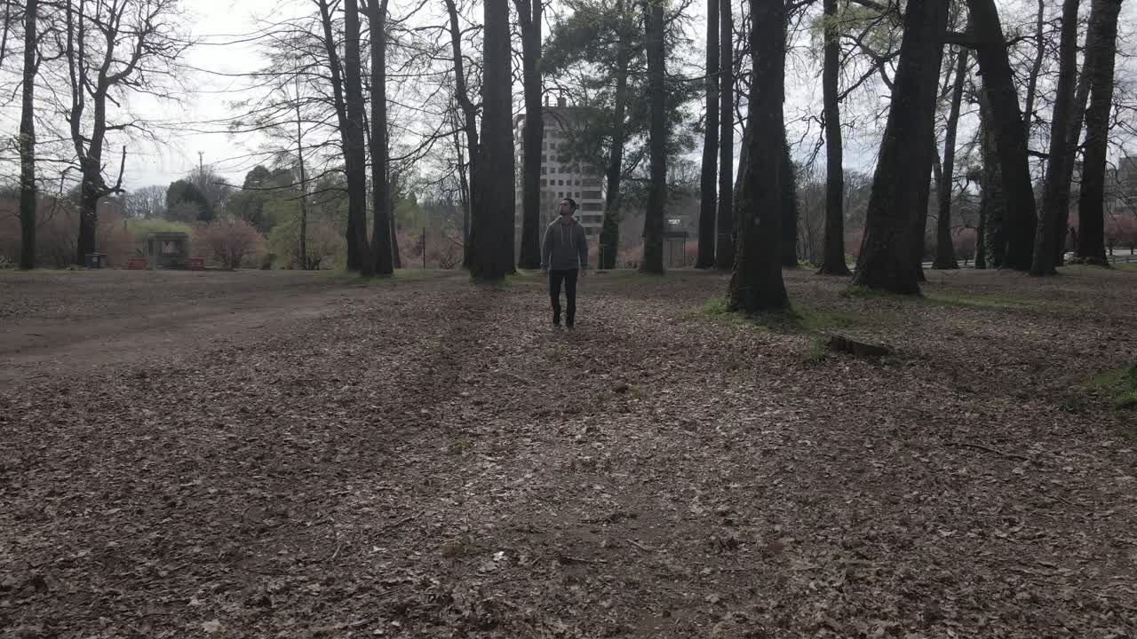 Man walking into the camera alone in the woods in a park