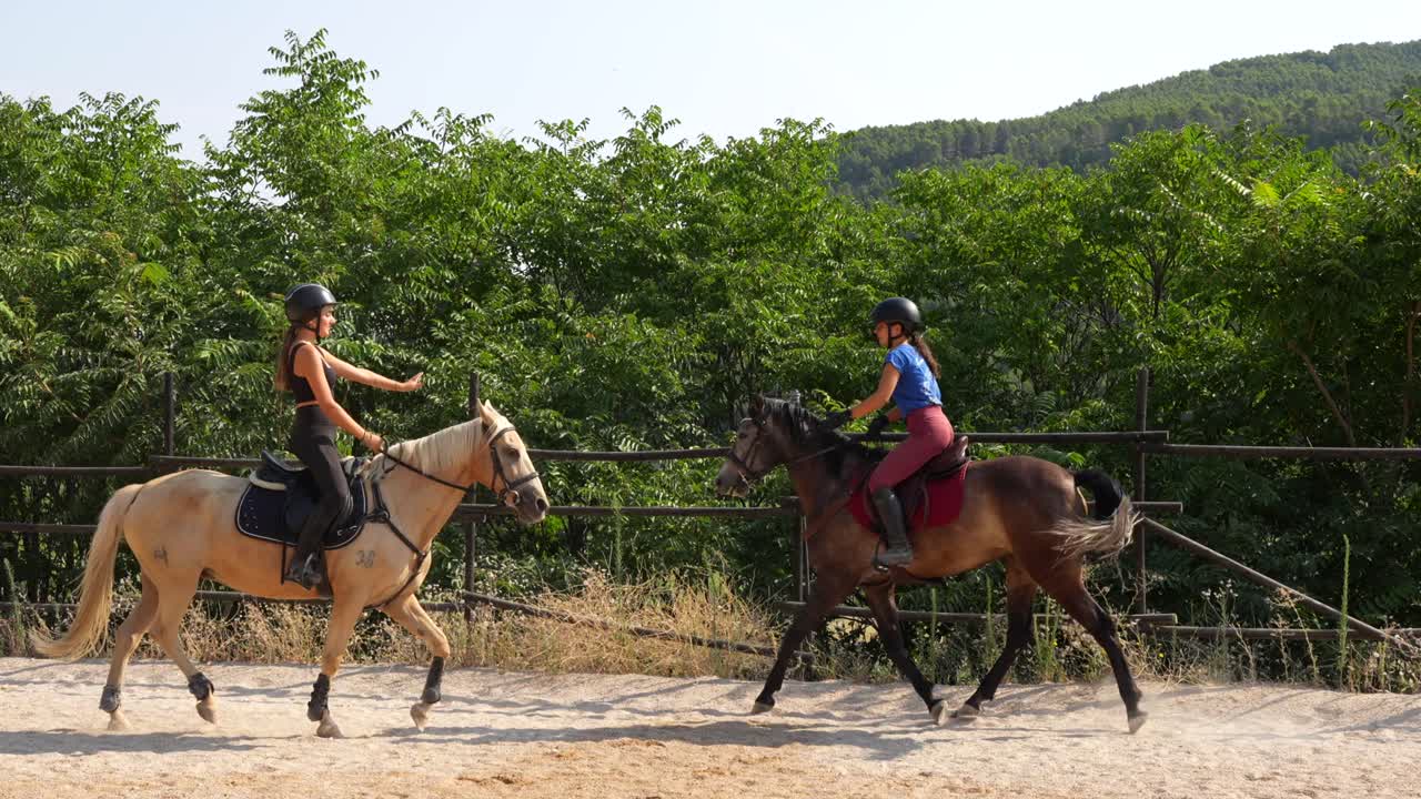 Two horse riders exchange a sportsmanlike high five on passing after a good round of work