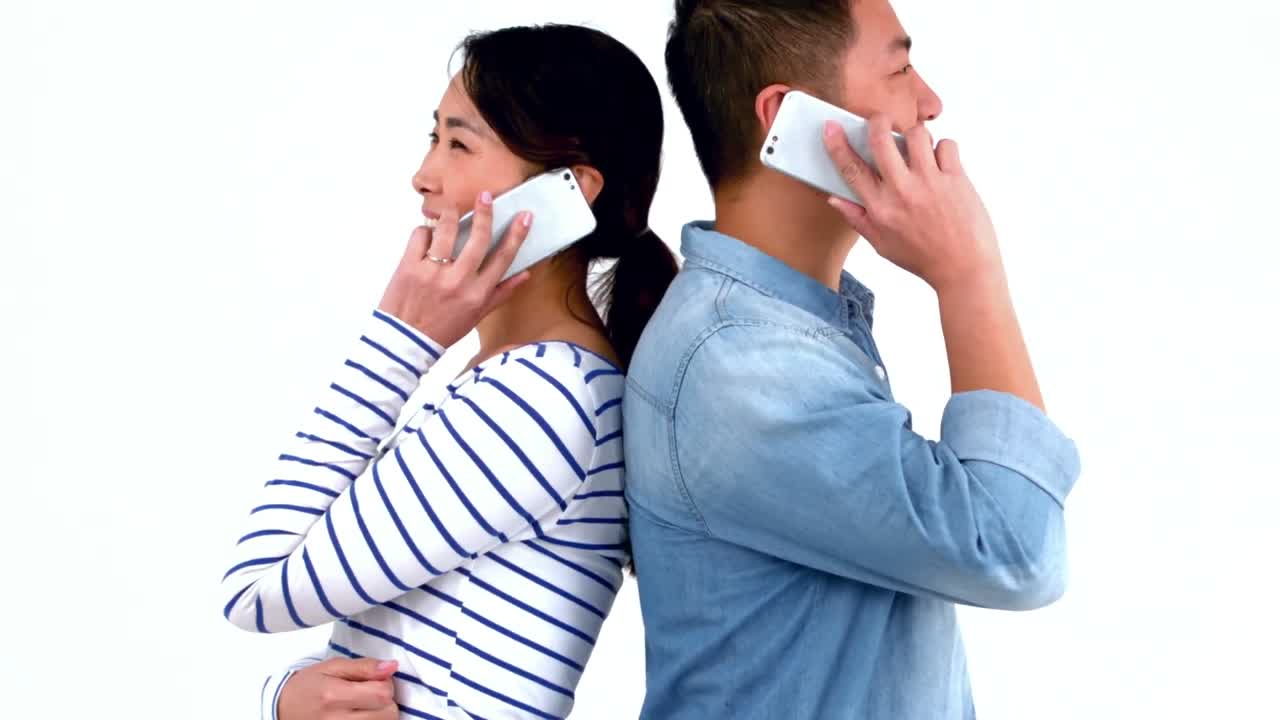 背中合わせで電話をする笑顔のカップル