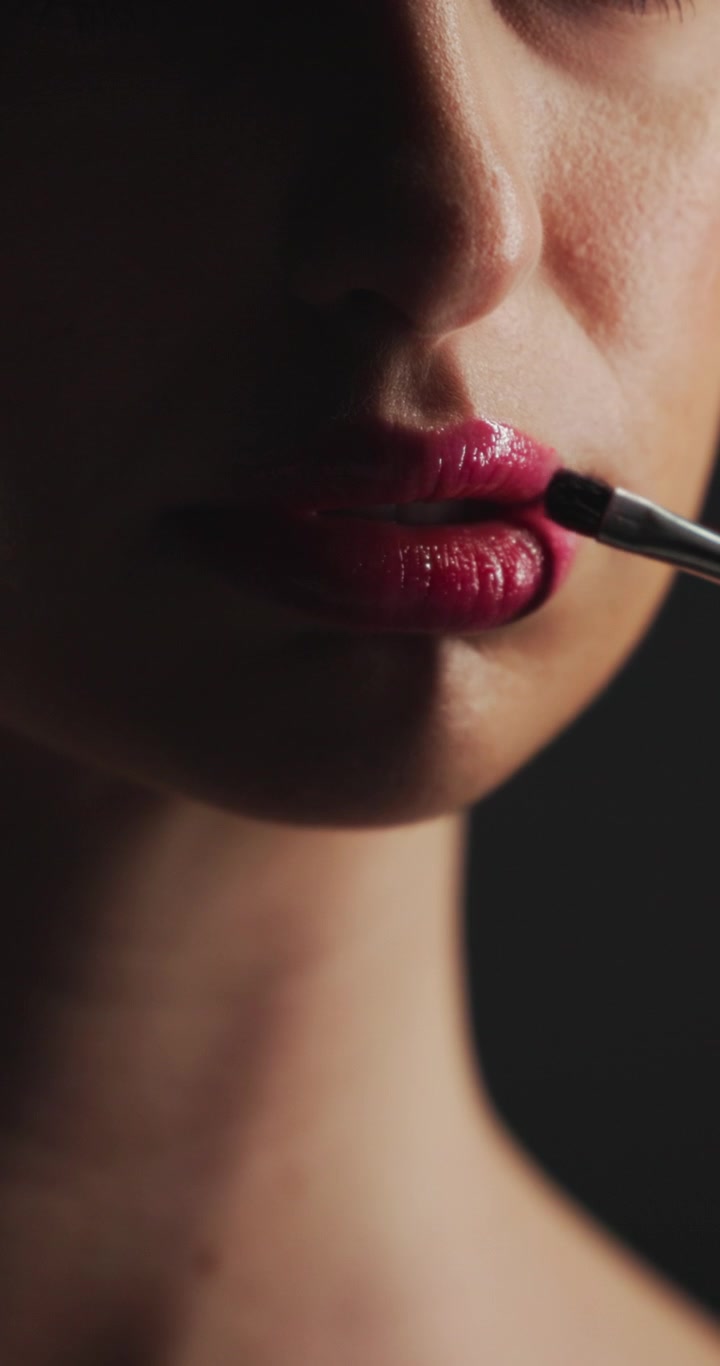 Close-up of Woman Applying Red Lipstick with Makeup Brush