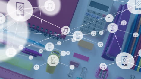 animation of network of music and media icons over school stationery on desk