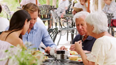 young adult and senior couple eating together outside a cafe