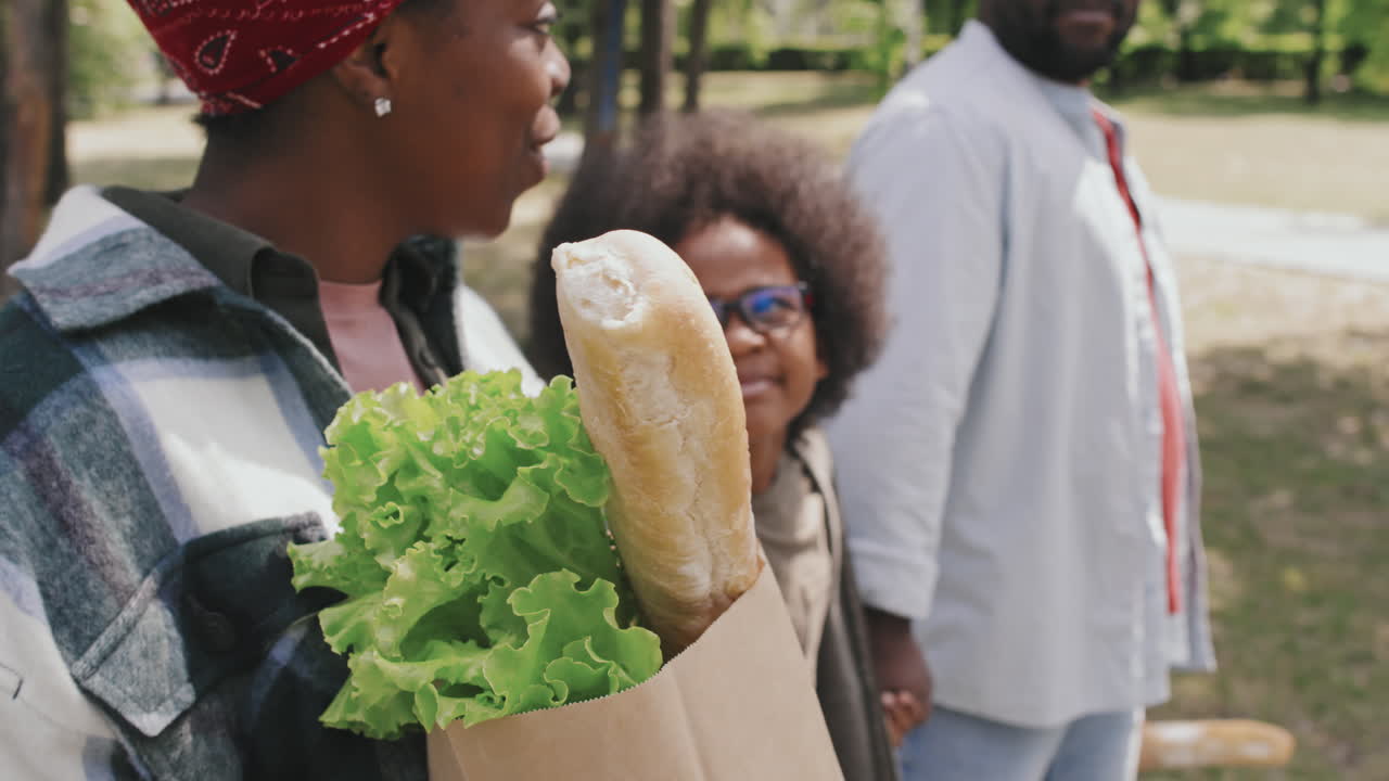 Heureuse famille transportant des produits alimentaires dans des sacs de courses sur le chemin du retour