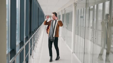 Stylish-cheerful-man-dancing-in-headphones-in-the-hallway