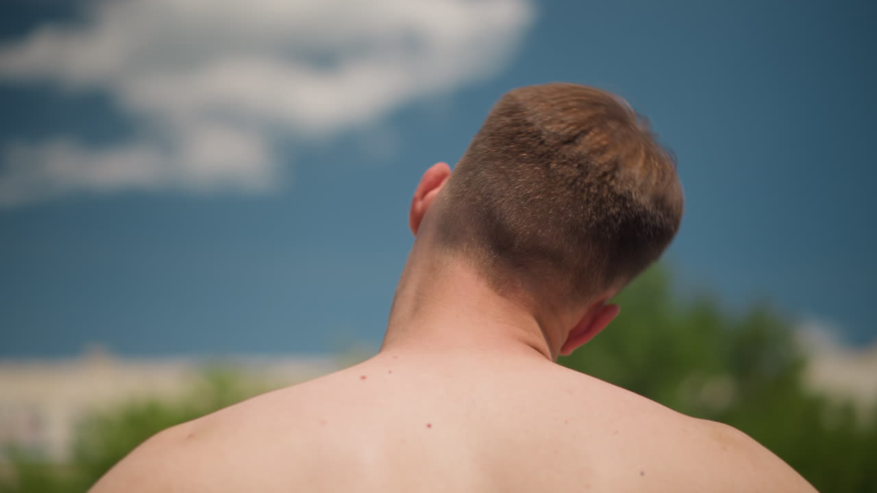 야외에서 뒤통수가 보이는 남성의 헤어컷 뒷모습, 도시 배경에서 젊은 남성의 뒷모습을 상세한 피부 묘사로 보여주는 이미지, 도시 환경에서 목과 헤어컷을 보여주는 젊은 백인 남성의 인물 사진