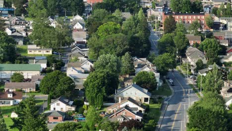 american city neighborhood with houses along tree-lined road in summer. aerial zoom wide shot. historic buildings with different architectural style and colors. sunset evening in usa