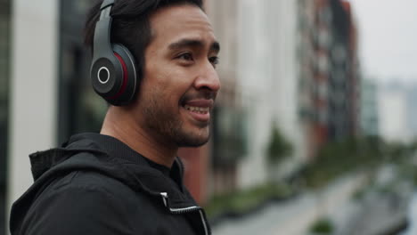 hombre sonriente escuchando música con auriculares en la ciudad