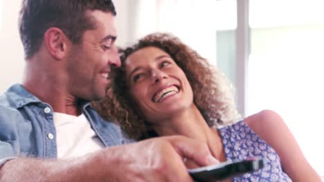 Cute-couple-watching-tv-and-using-remote-on-the-couch