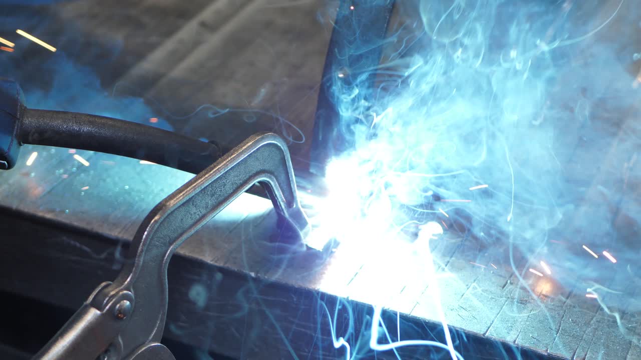 용접기를 사용하여 금속 강철과 철을 사용한 근접 작업, 밝은 스파크 및 매우 느린 동작으로 깜박임