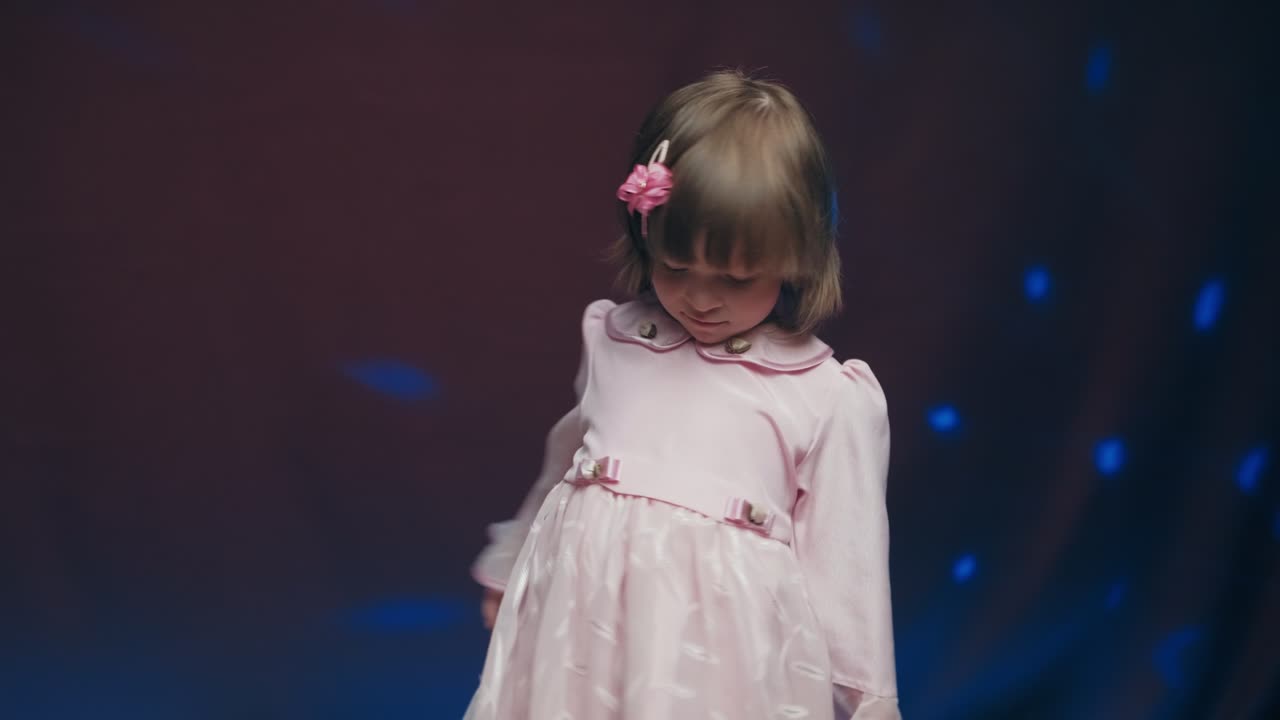 una niña linda en un vestido rosa vintage está girando en el baile y regocijándose