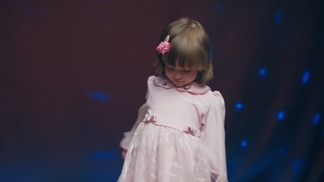 cute little girl in vintage pink dress is spinning in dance and rejoicing