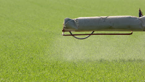 Tele-slomo-shot-of-crop-sprayer-boom-arm,-spraying-toxic-pesticides-on-field