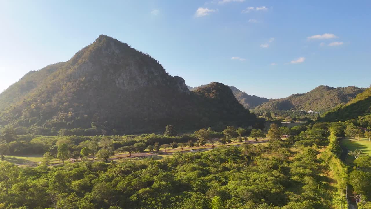 La videocamera di un drone scivola su una fitta foresta verde verso una prominente cima calcarea.