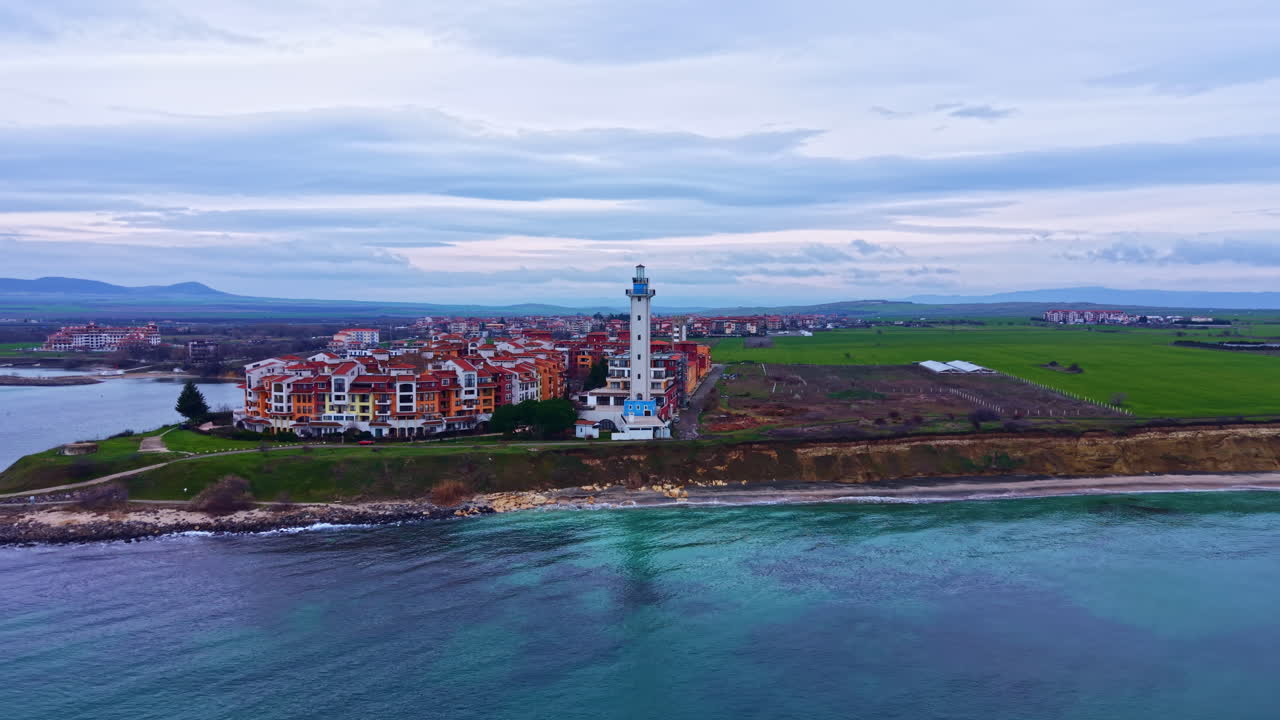Paesaggio costiero con un faro ed edifici residenziali vicino all'acqua durante il giorno
