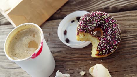 marca de lápiz labial en la taza de café y un donut de chocolate medio comido con salpicaduras