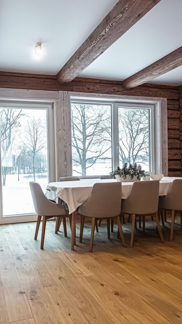A smooth panning hyperlapse reveals the warm and cozy interior of a Latvian log home, from the dining area to the living room, with a beautiful snowy winter landscape outside