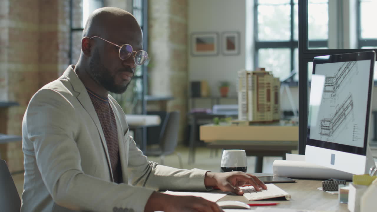 Architect working on computer in office with building model