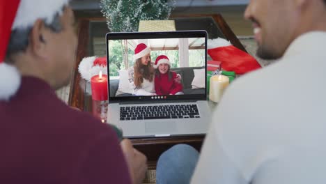 Lächelnder-Gemischtrassiger-Vater-Und-Sohn,-Die-Einen-Laptop-Für-Einen-Weihnachtsvideoanruf-Mit-Einer-Glücklichen-Familie-Auf-Dem-Bildschirm-Benutzen