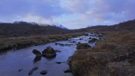 zoom in shot of tranquil bruara river in iceland surrounded by rocks and natural plants during cloudy day