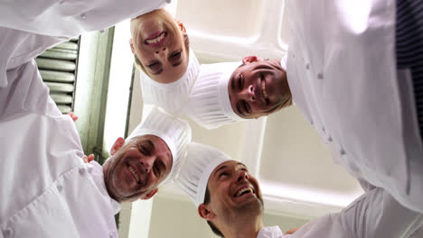 team of chefs standing in circle looking down at camera