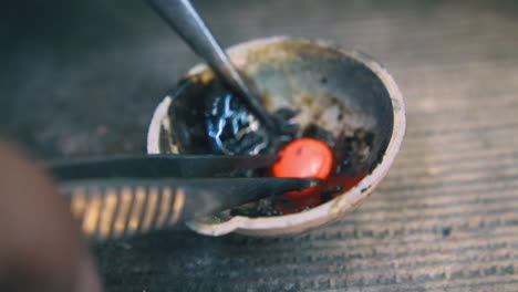 jeweler takes hot gold drop from fireproof cup closeup