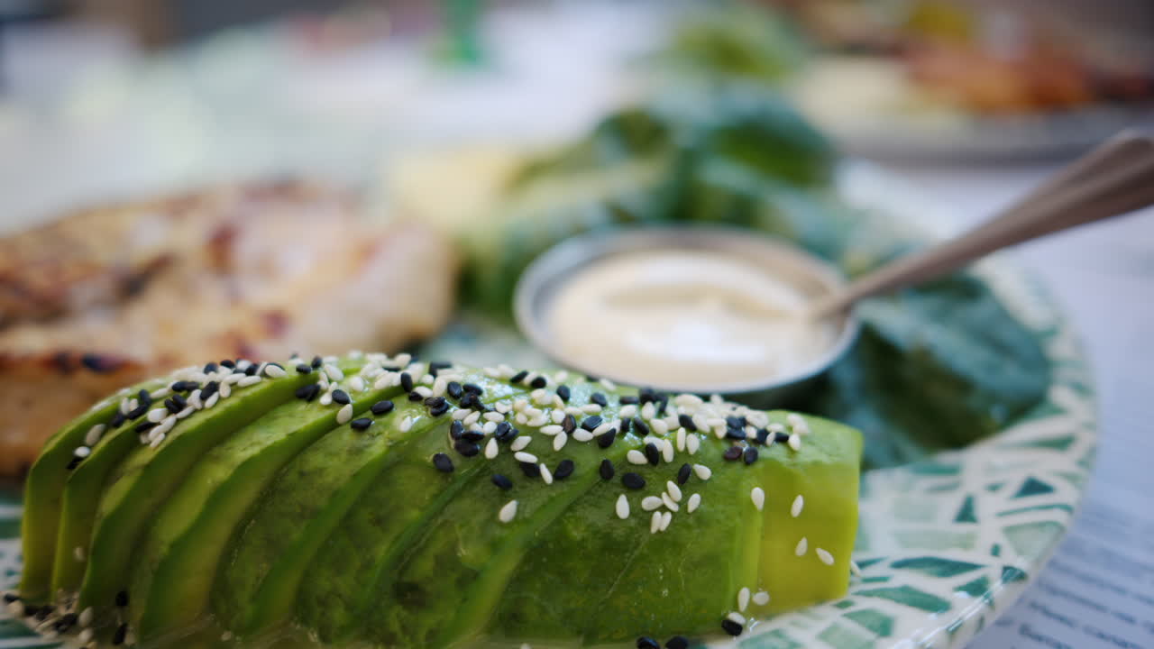 Close up of a piece of a cooked chicken tender with avocado and sauce