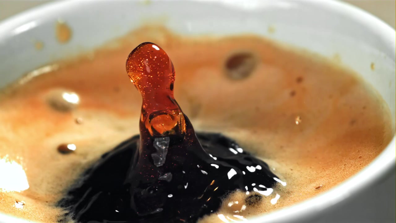 Goccia di caffè al rallentatore che schizza nell'espresso con crema