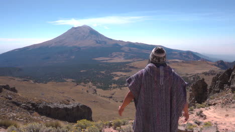 back view of man trekker standing and looking at steaming active popocatepetl volcano