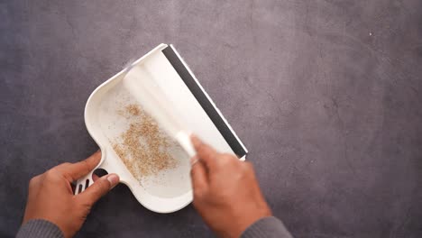cleaning up dust with a dustpan and brush