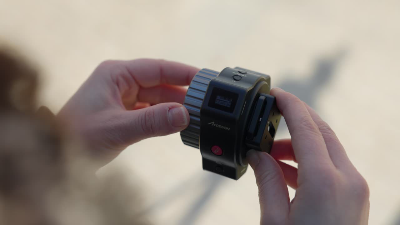 Close-up shot of hands adjusting the focus module while filming