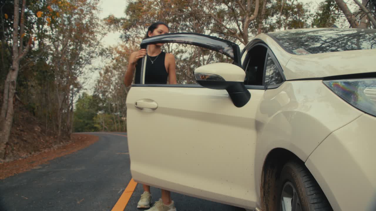 Woman getting out of a car in a forest