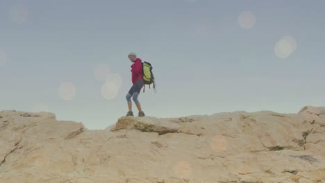 Animation-of-light-spots-over-caucasian-woman-walking-in-mountains