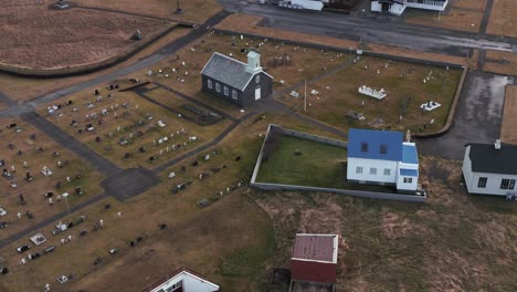 historic graveyard with church revealing residential neighborhood in iceland, aerial