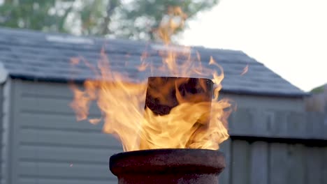 cámara lenta: una vista de ángulo bajo de una tabla que sobresale de la parte superior de una chimenea mientras las llamas se elevan a su alrededor