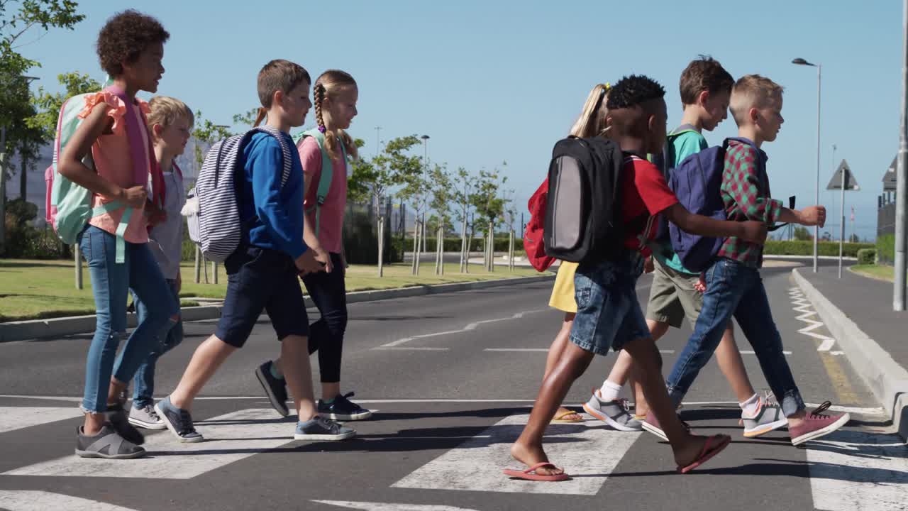 grupo de niños con bolsas escolares cruzando la carretera