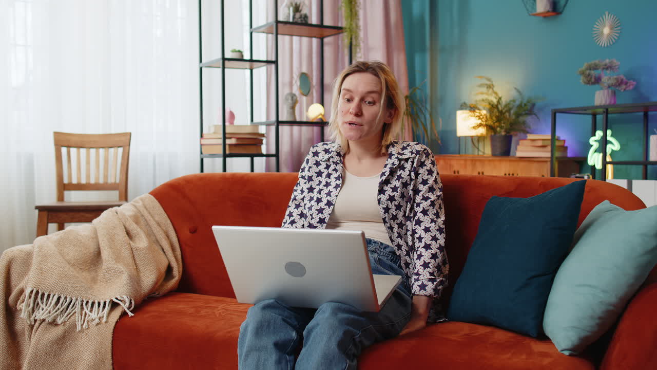 Overjoyed young woman talking to friend by video call using laptop smile wave hand share good news